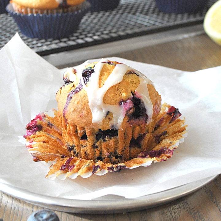 One baked Blueberry Muffin with the wrapper peeled off. by 2sistersrecipes.com