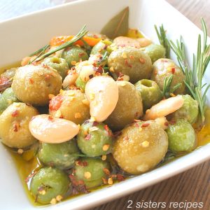 A square white bowl filled with marinated olives and beans.
