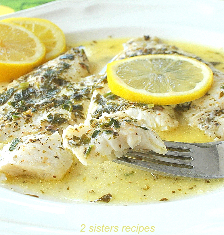 A forkful of white fish in lemon sauce on a white plate. by 2sistersrecipes.com