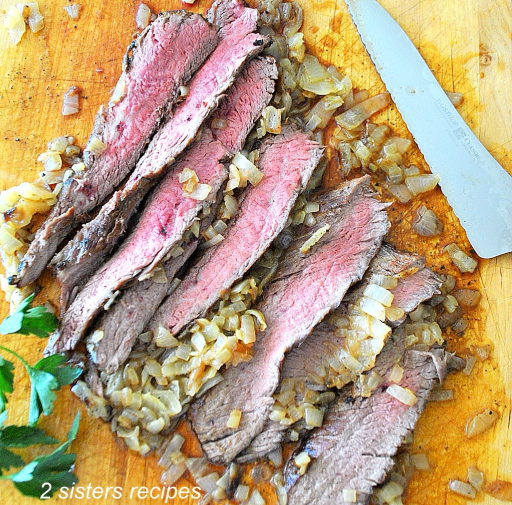 Sliced of steak carved on a cutting board. by 2sistersecipes.com