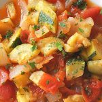 A bowl of freshly chopped zucchini and tomatoes soup.