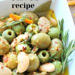 A white bowl filled with marinated olives and white beans.