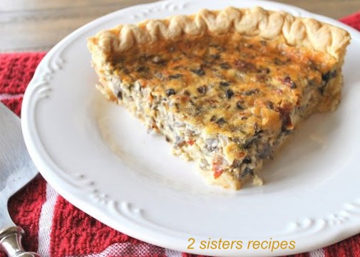 A slice of a mushroom and sundried quiche served on a white plate. 