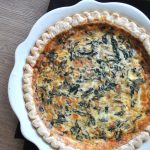 A baking dish with a baked crust filled with spinach and cheese.