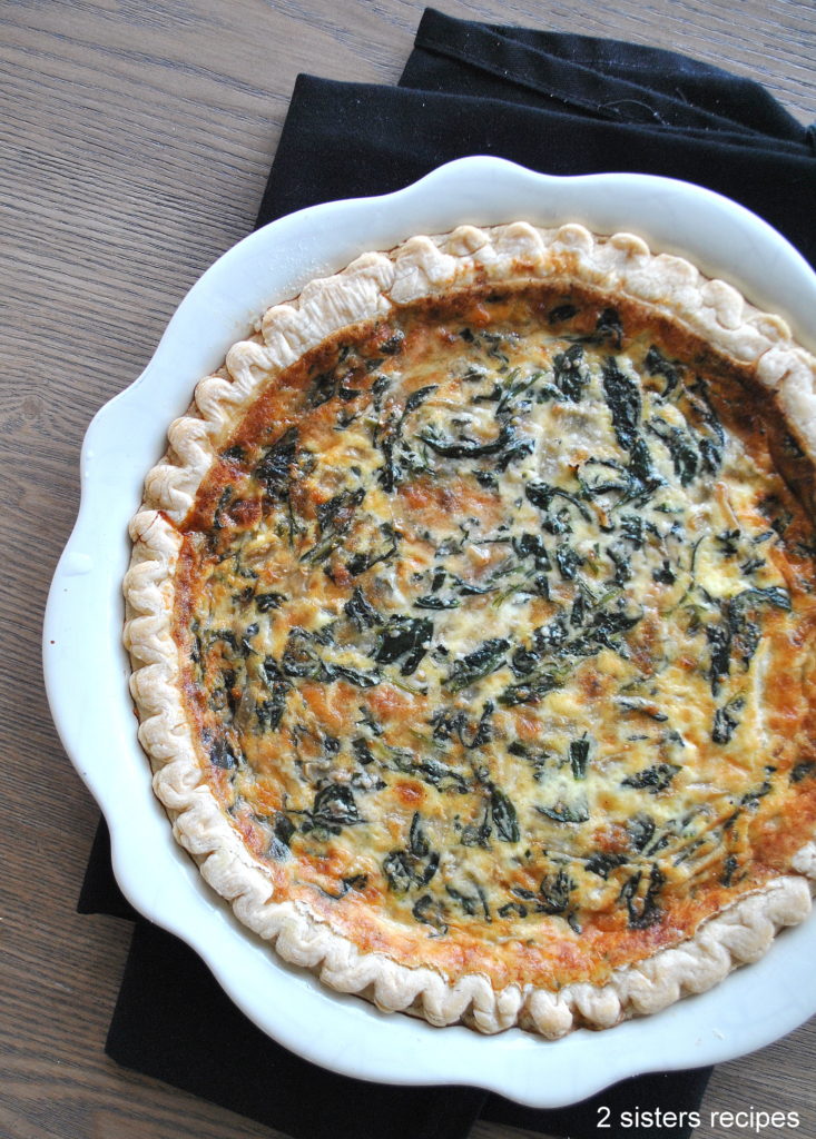 A baking dish with a baked crust filled with spinach and cheese.