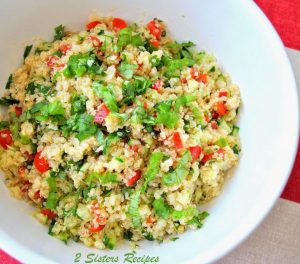 A quinoa salad filled with parsley and tomatoes served in a white salad bowl.