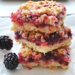 Three Blackberry Lemon Crumble Bars are piled on top of each other.