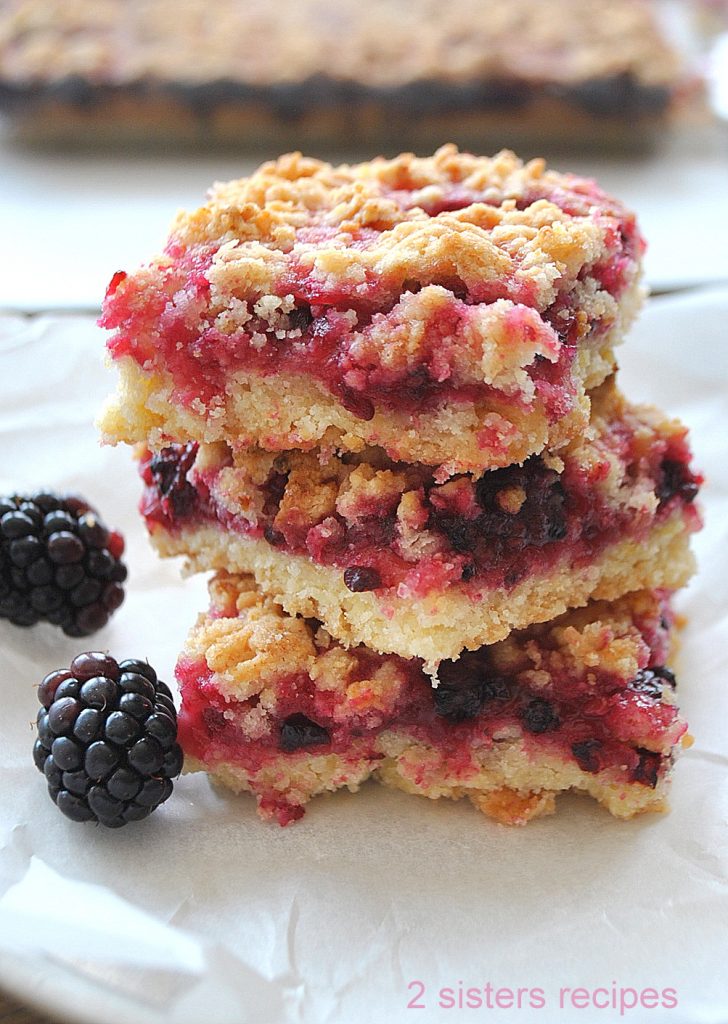 Three Blackberry Lemon Crumble Bars are piled on top of each other.