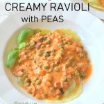 A plate filled with round ravioli covered with a pink sauce with peas.