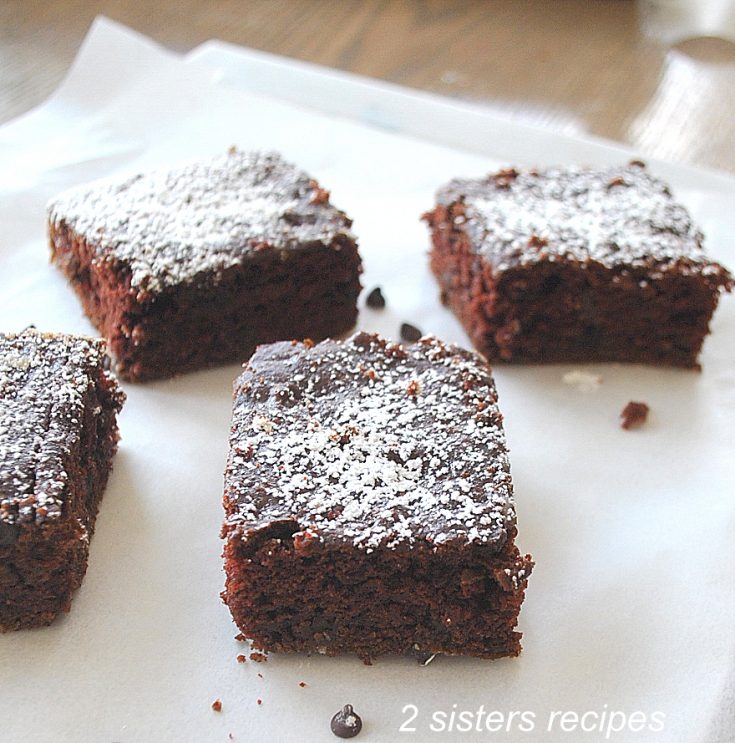 Four brownies on sheet of wax paper. by 2sistersrecipes.com