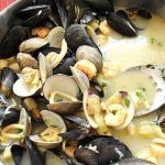 Mixed seafood in a wide pot on the table.