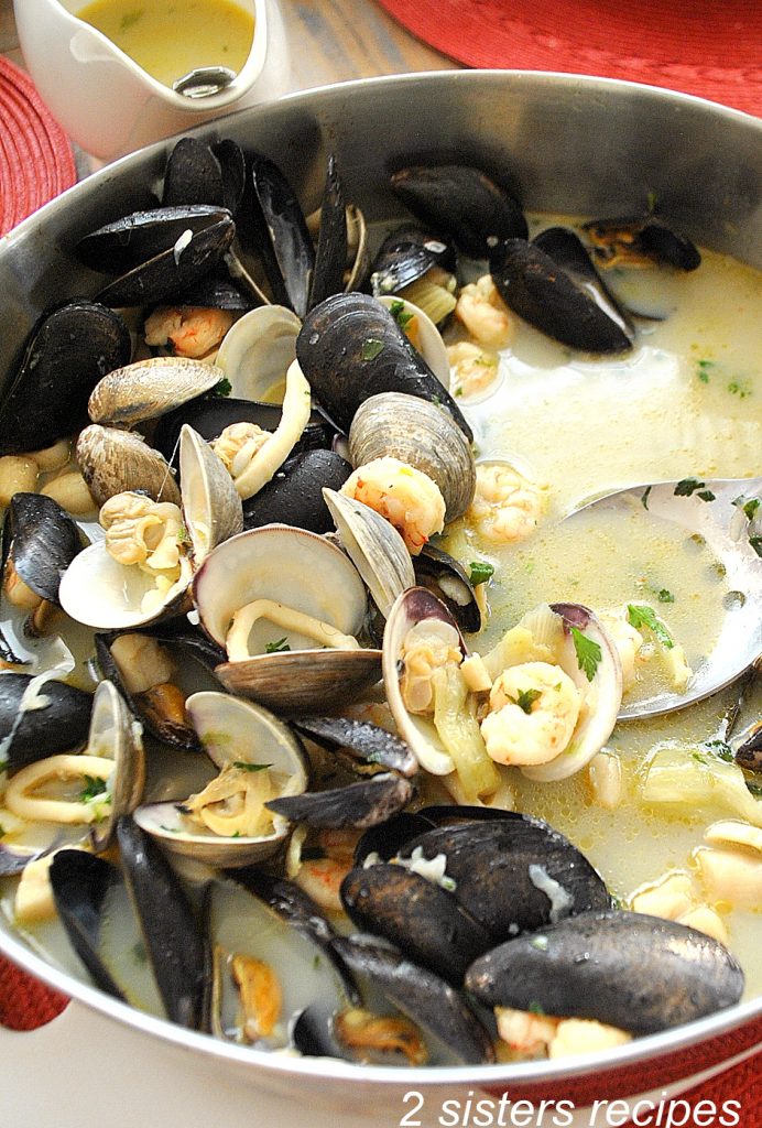 Mixed seafood in a wide pot on the table. by 2sistersrecipes.com 