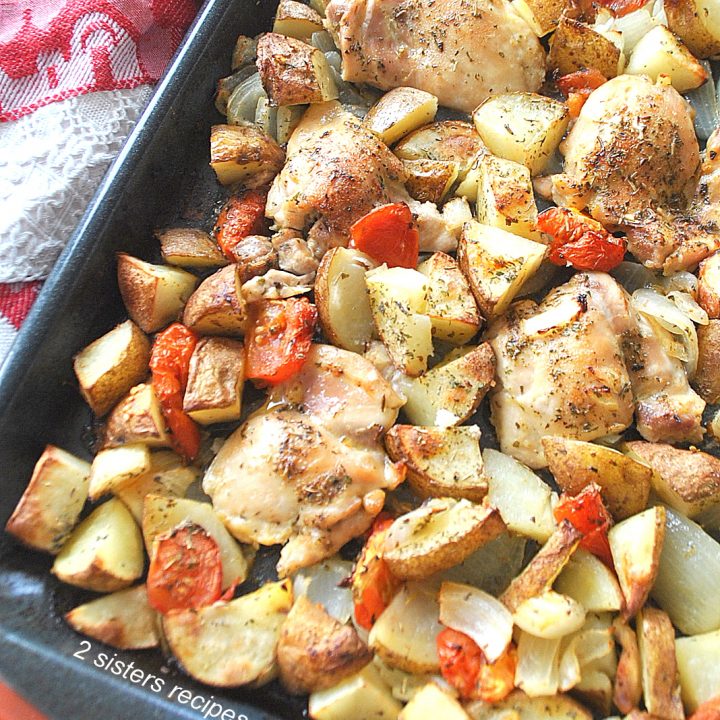 A large sheet pan filled with baked chicken thighs and veggies.