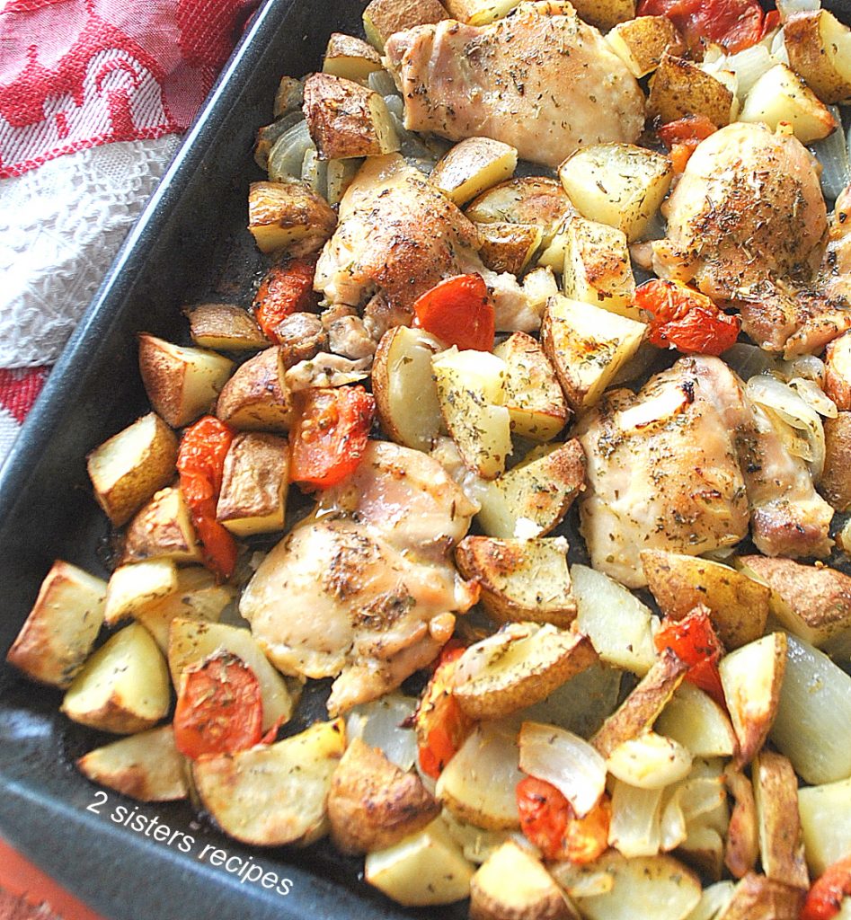 A large sheet pan filled with baked chicken thighs and veggies.