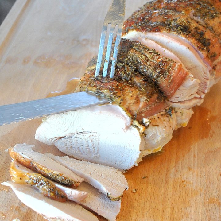 Carving a turkey breast on a wooden cutting board. by 2sistersrecipes.com