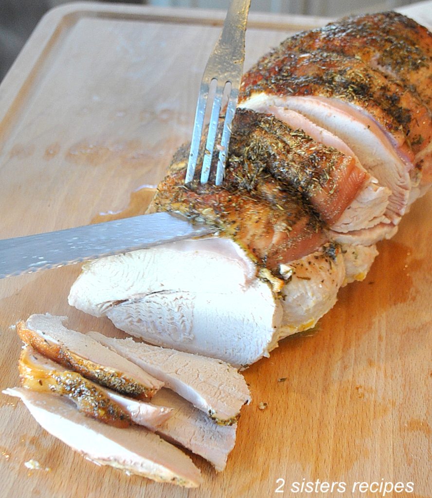 Carving a turkey breast on a wooden cutting board. by 2sistersrecipes.com