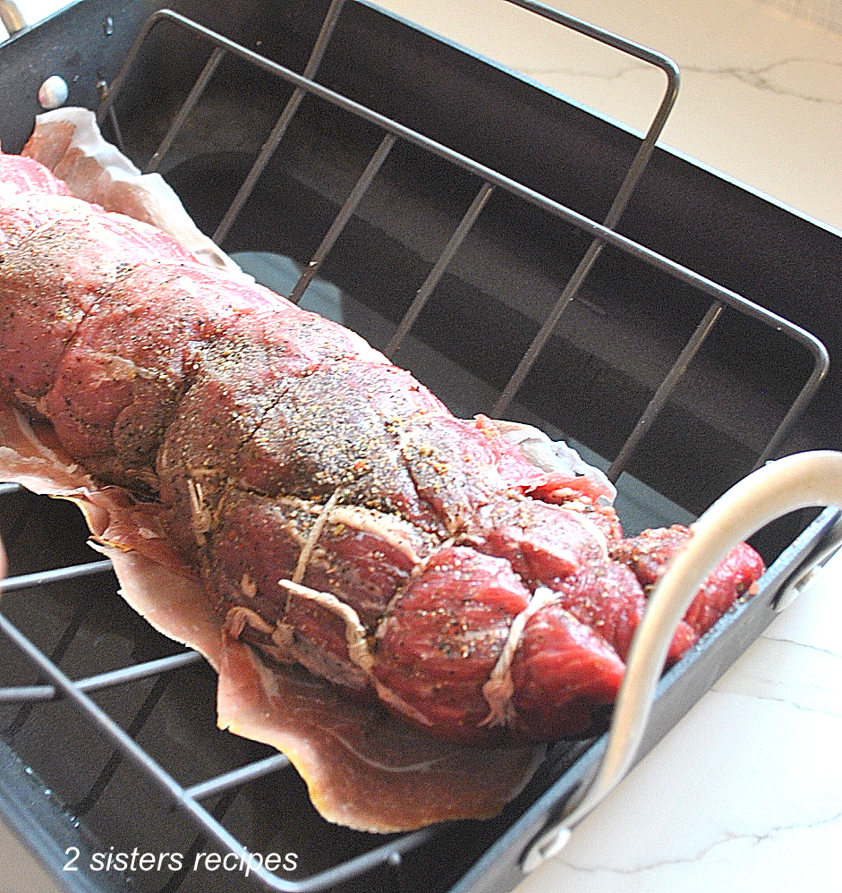 A filet mignon roast is sitting on a rack in the roasting pan. by 2sistersrecipes.com 