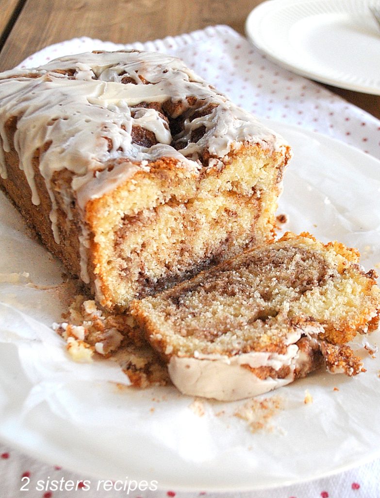  A loaf of bread with glaze on top, a sliced to see the swirl of cinnamon inside. 