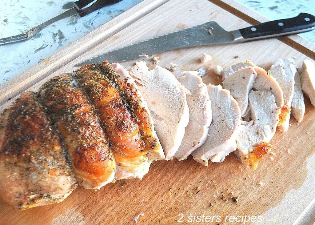 A turkey breast carved on a wood carving board. by 2sistersrecipes.com