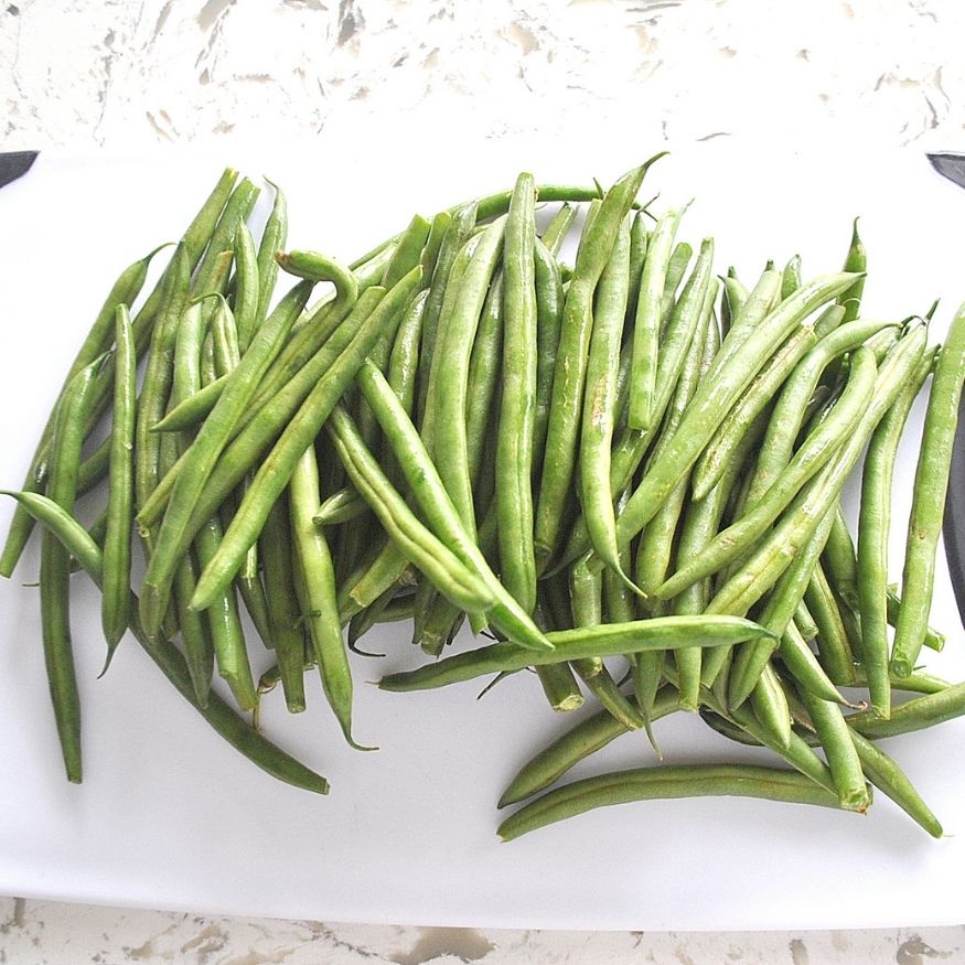 A photo of fresh green beans on a white cutting board. by 2sistersrecipes.com
