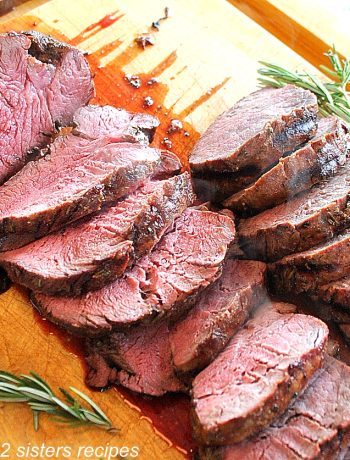 Beef Tenderloin is sliced on a cutting board.by 2sistersrecipes.com