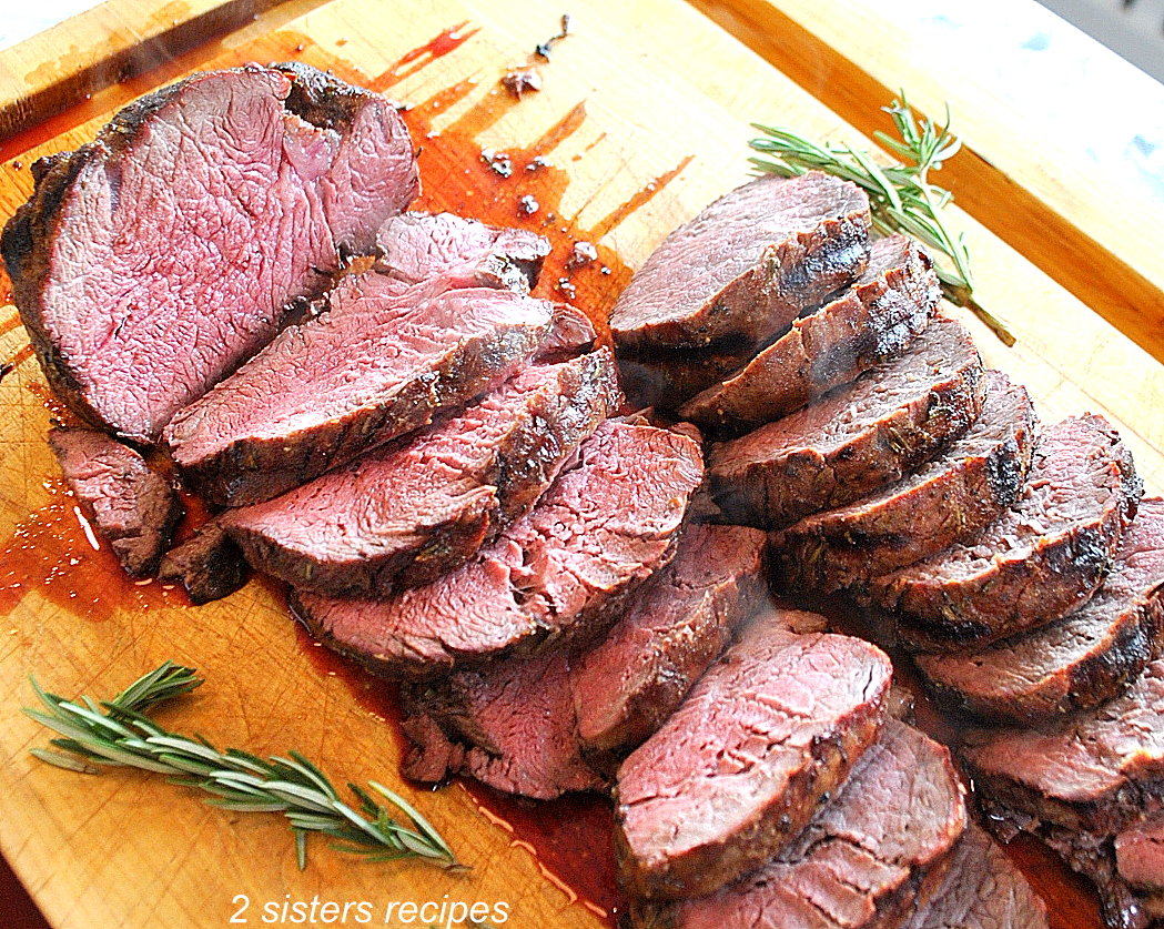Beef Tenderloin is sliced on a cutting board.by 2sistersrecipes.com