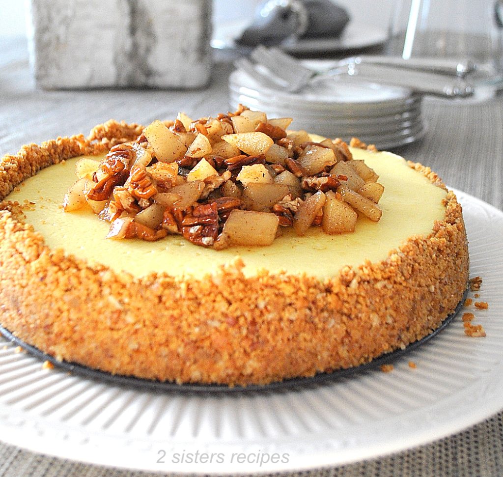 A beautiful cheesecake topped with chopped pears and pecans in maple sauce.