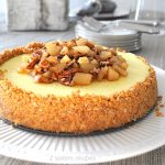 A beautiful cheesecake topped with chopped pears and pecans in maple sauce.