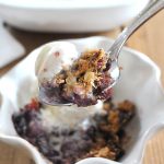 A spoonful of apple cherry crisp with ice cream on top.