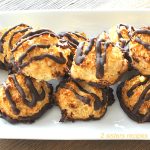 A white platter filled with macaroon cookies with chocolate drizzled over them.