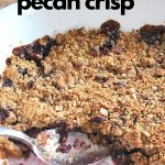 A baked apple cherry crisp with a crumble on top and a spoon inside the baking dish.