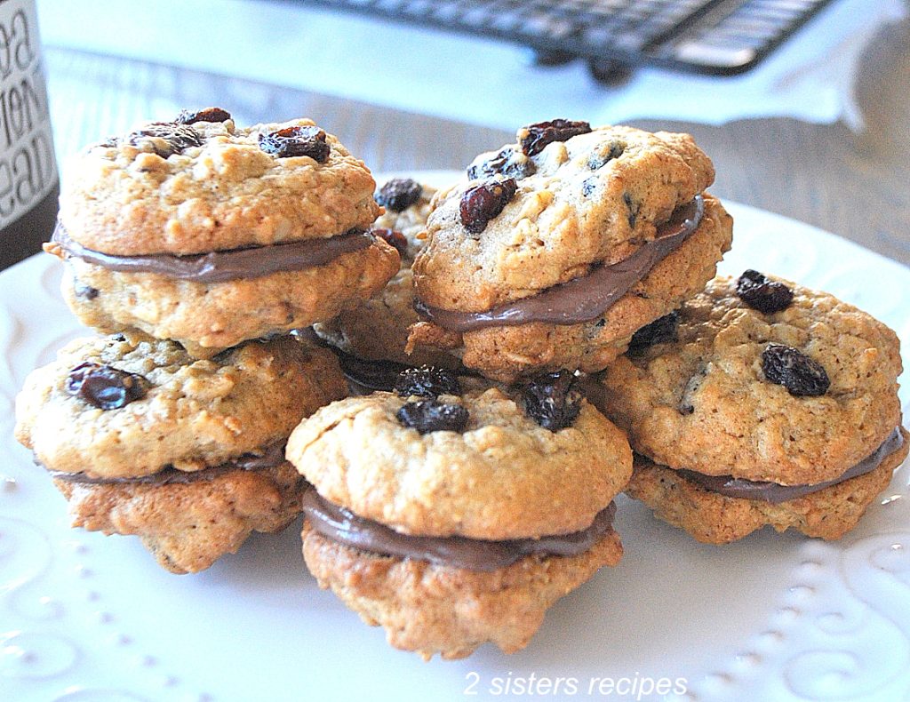 A bunch of cookies piled on a white plate. by 2sistersreipes.com
