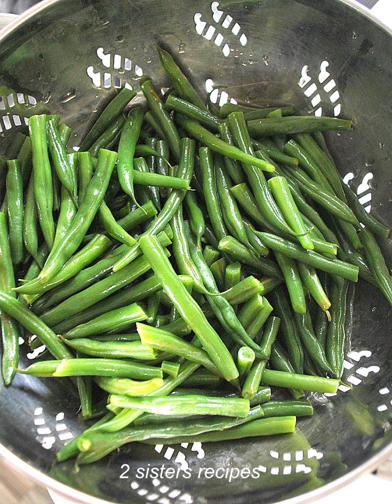 String beans drain in a colander. by 2sistersrecipes.com