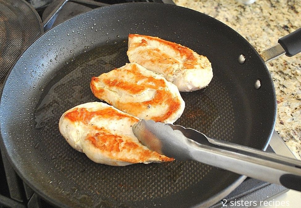 3 chicken breasts cooking in a black skillet. by 2sistersrecipes.com