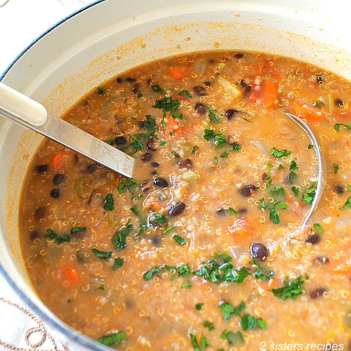 A large pot filled with Black Bean and Quinoa Soup and a ladle inside the pot.