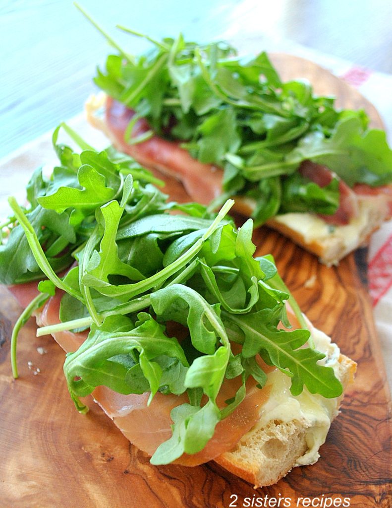 Close up photo of two bread pizza's on a wooden board. by 2sistersrecipes.com