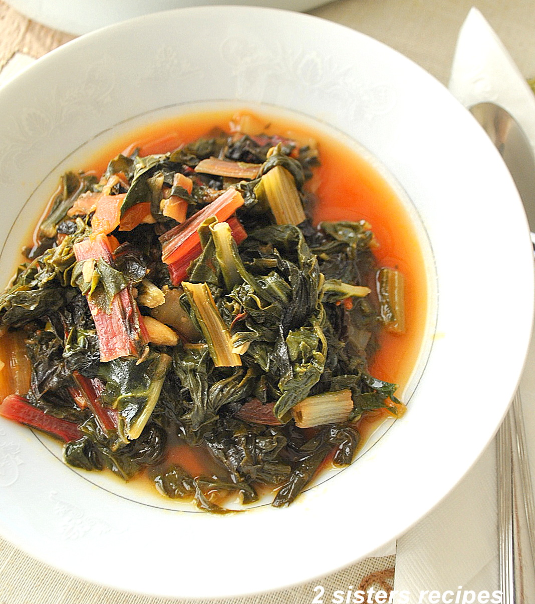 A white plate filled with cooked Swiss Chard. by 2sistersrecipes.com