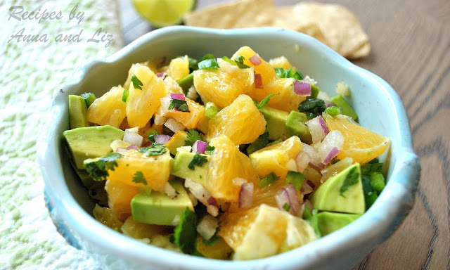 A blue bowl with chopped oranges and avocado and topped with cilantro.