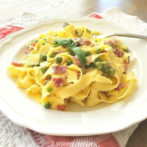 White plate with a serving of Pappardelle with Prosciutto and Peas.