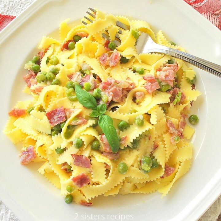 White dinner plate with a serving of Pappardelle with Prosciutto and Peas.