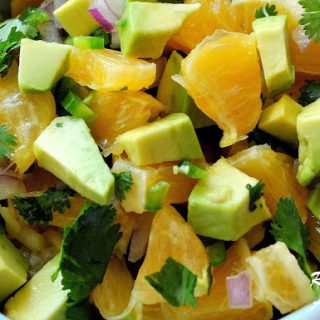 An orange and avocado salsa topped with fresh chopped cilantro is served in a blue bowl.