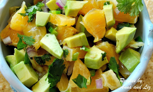 An orange and avocado salsa topped with fresh chopped cilantro is served in a blue bowl.