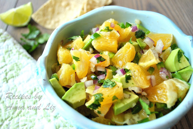 A blue bowl filled with freshly chopped avocados and oranges.