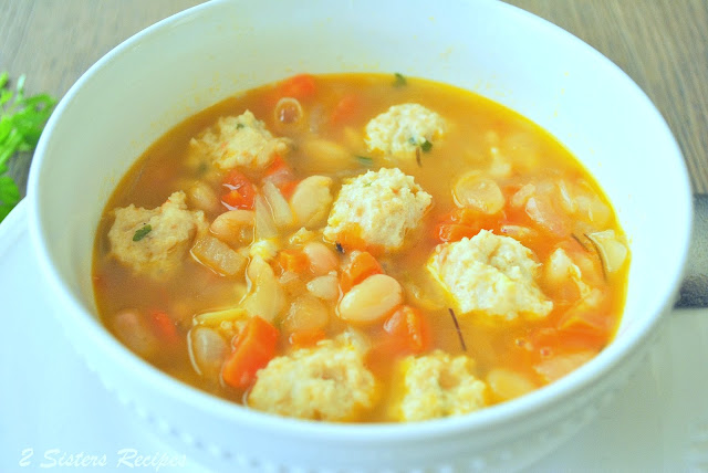 A white bowl of soup with mini meatballs. by 2sistersrecipes.com