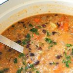 A Dutch oven pot filled with a black bean and quinoa soup.
