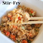 A set of chop sticks with cauliflower rice and veggies stir-fry.