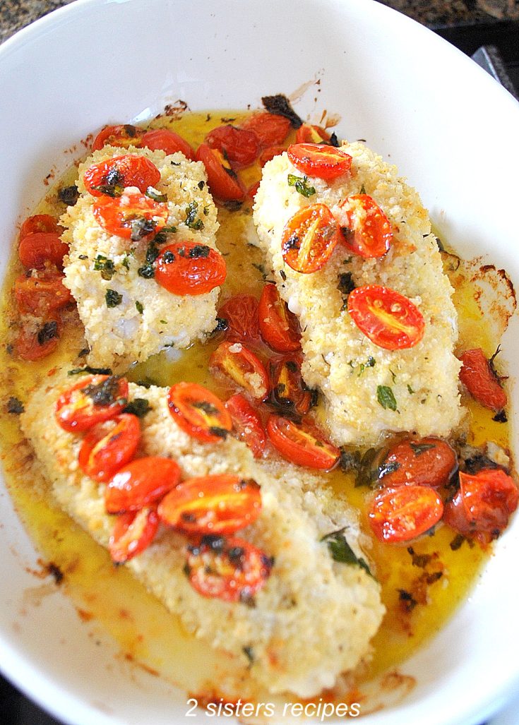 Baked cod with cherry tomatoes in a white baking dish.