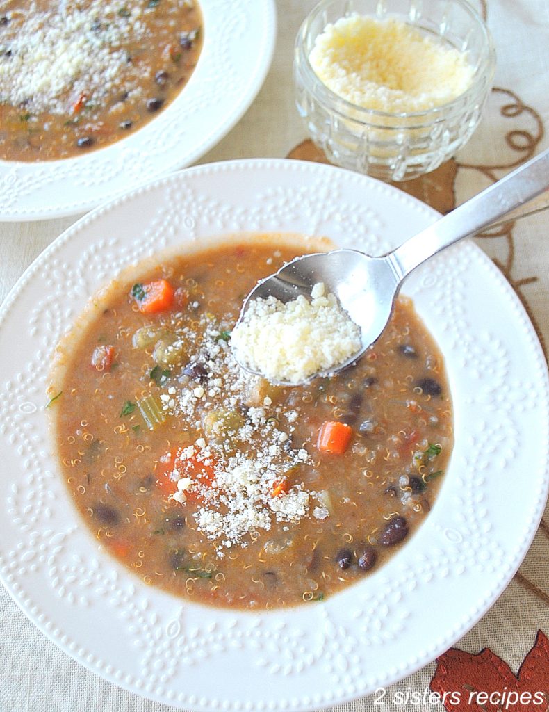 A spoonful of grated cheese sprinkling over a bowl of soup. by 2sisterserecipes.com