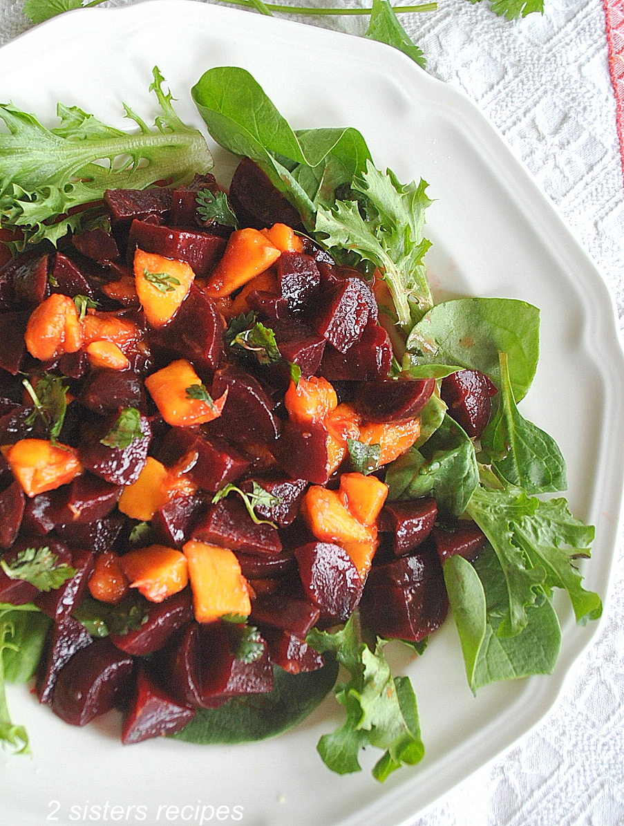 A white plate with lettuce, chopped beets and mango on it.