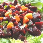 Chopped beets and mango set on a bed of lettuce for serving.